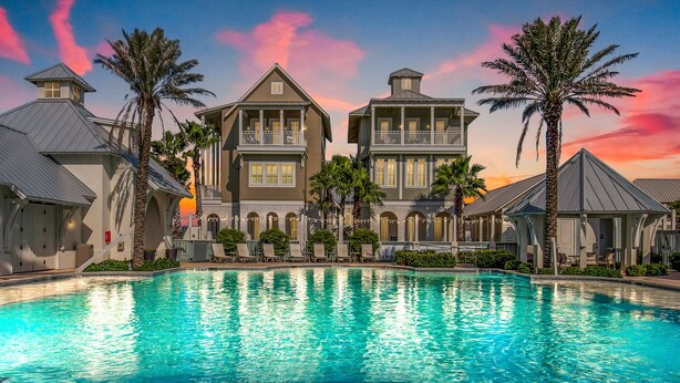 A large swimming pool with a view of a resort-style building with multiple balconies and palm trees. - Townhouse + loft with private balcony, heated pool, gym, beach access & W/D (Port Aransas)