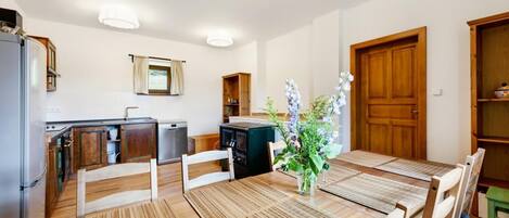 Une cuisine compacte dotée d’appareils électroménagers modernes, un coin repas agrémenté de sets de table en bambou et de meubles en bois.