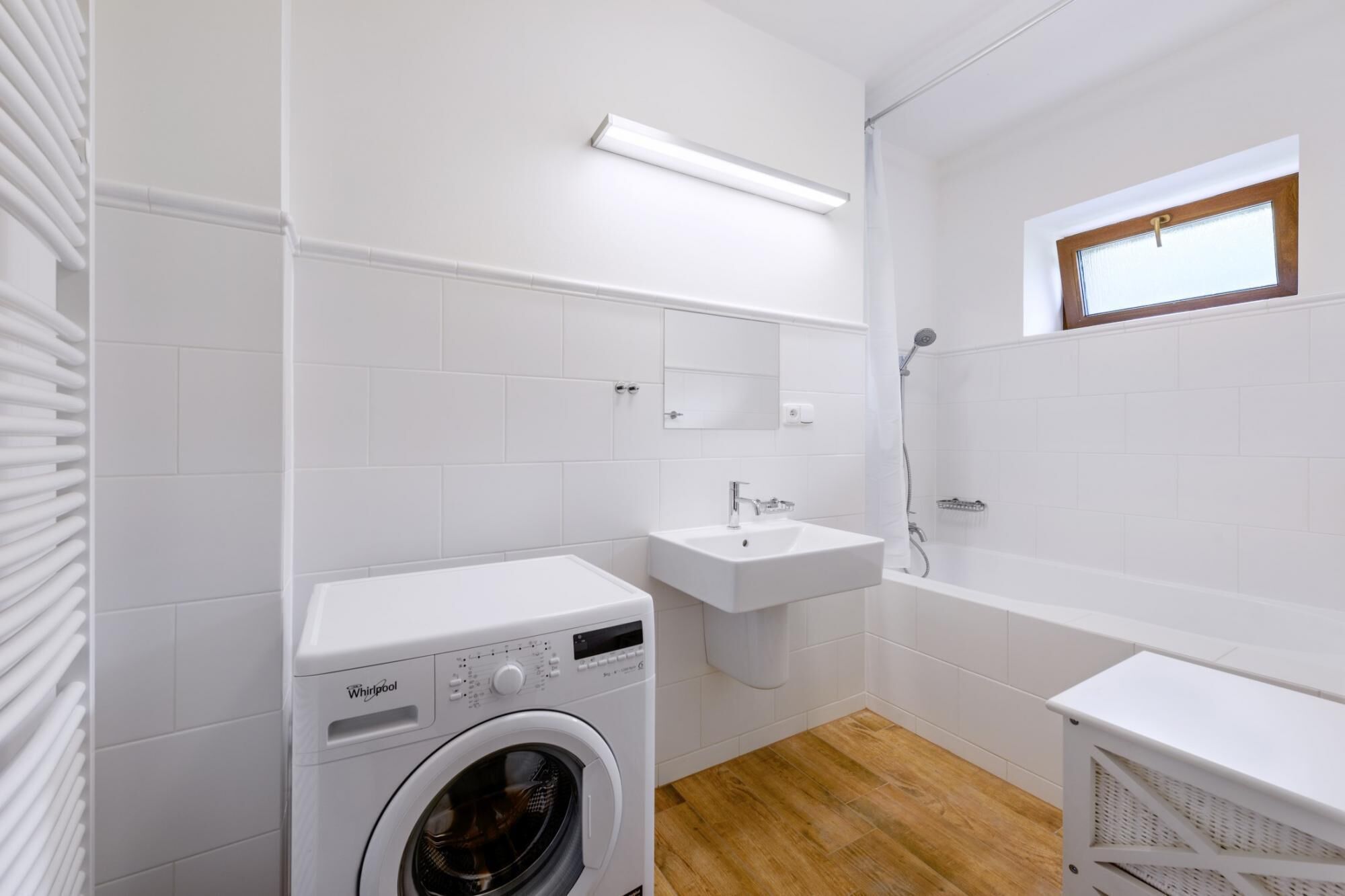 A compact, modern bathroom with a built-in washer, a sink, and a shower.