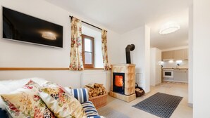 Una sala de estar acogedora con un sofá, una chimenea, un televisor y una cocina al fondo.