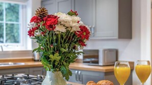 Un comptoir de cuisine orné d’un vase de fleurs, de croissants et de verres de jus d’orange.
