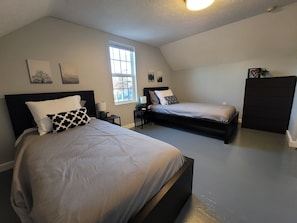 Een slaapkamer met twee bedden, een raam en een plafondlamp.