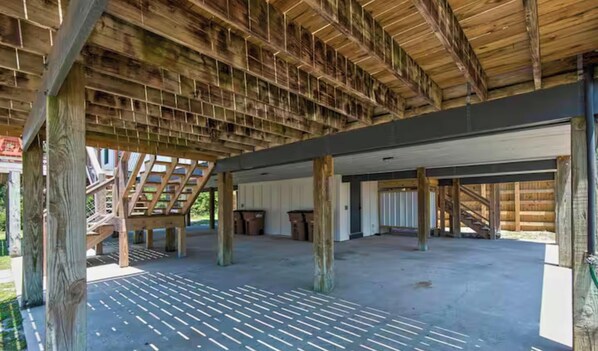 Ein offener überdachter Bereich mit geneigter Decke, Holzbalken und einem Betonboden.