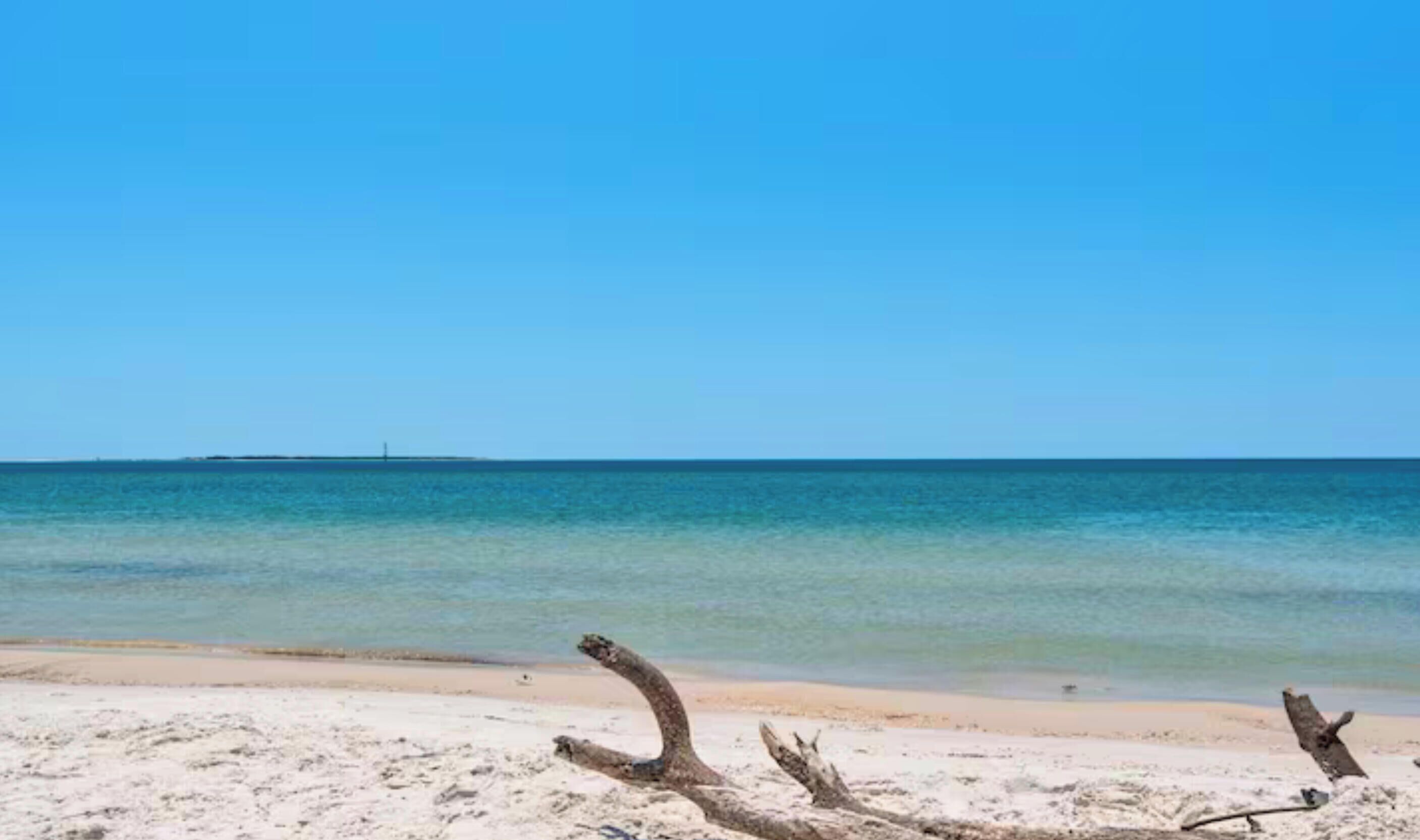 Una playa con aguas azul turquesa y una orilla arenosa.