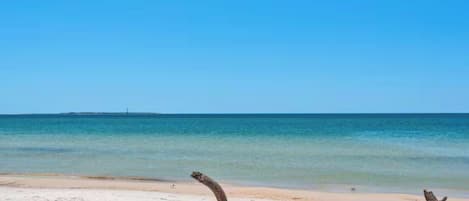 Una playa con aguas azul turquesa y una orilla arenosa.