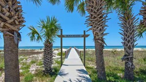 A pathway leading to the beach with palm trees on either side and a sign indicating beach access. - Steps to the Beach 3BR Coastal Home Sleeps 10 (Port Saint Joe)