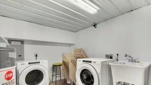 Una sala amb bugaderia, amb dues rentadores, una cadira apilada i un rentaplat.