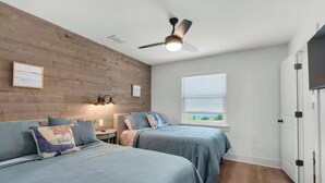 A bedroom with two beds, a ceiling fan, a window with blinds, and a door. - Steps to the Beach 3BR Coastal Home Sleeps 10 (Port Saint Joe)