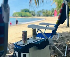 A beach chair with a can of beer and a bottle on it.