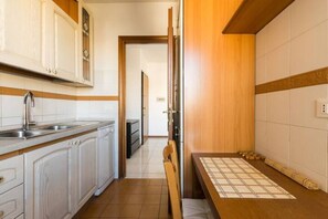 Une cuisine avec des meubles blancs, un plan de travail en bois et un revêtement mural en carreaux.