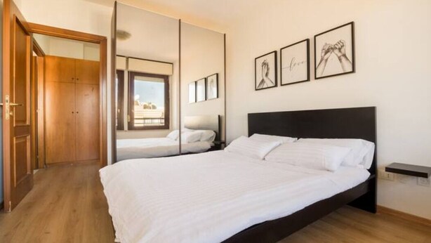 A bedroom with a large bed, a wooden wardrobe, a mirror, and framed pictures on the wall. - [PENTHOUSE ROME- 5 stars] elegant apartment (Roma)