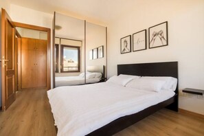 A bedroom with a large bed, a wooden wardrobe, a mirror, and framed pictures on the wall. - [PENTHOUSE ROME - 5-star] elegant apartment (Roma)