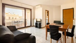 A modern living room with a sofa, dining table, and chairs. There is a sliding glass door leading to a balcony with a view of buildings. - [PENTHOUSE ROME- 5 stars] elegant apartment (Roma)