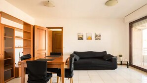 A modern living room with a dining area, a black sofa, wooden cabinets, and a sliding glass door. - [PENTHOUSE ROME- 5 stars] elegant apartment (Roma)
