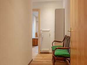 Enter a cozy space with a wooden floor and a door leading to a room with a radiator.