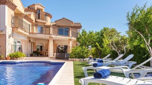 A poolside area with lounge chairs and a clear blue pool.