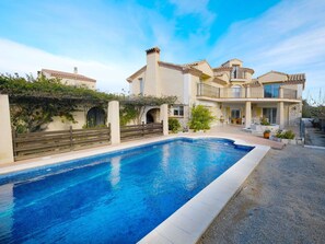 A two-story house with a swimming pool, a balcony, and a garden.