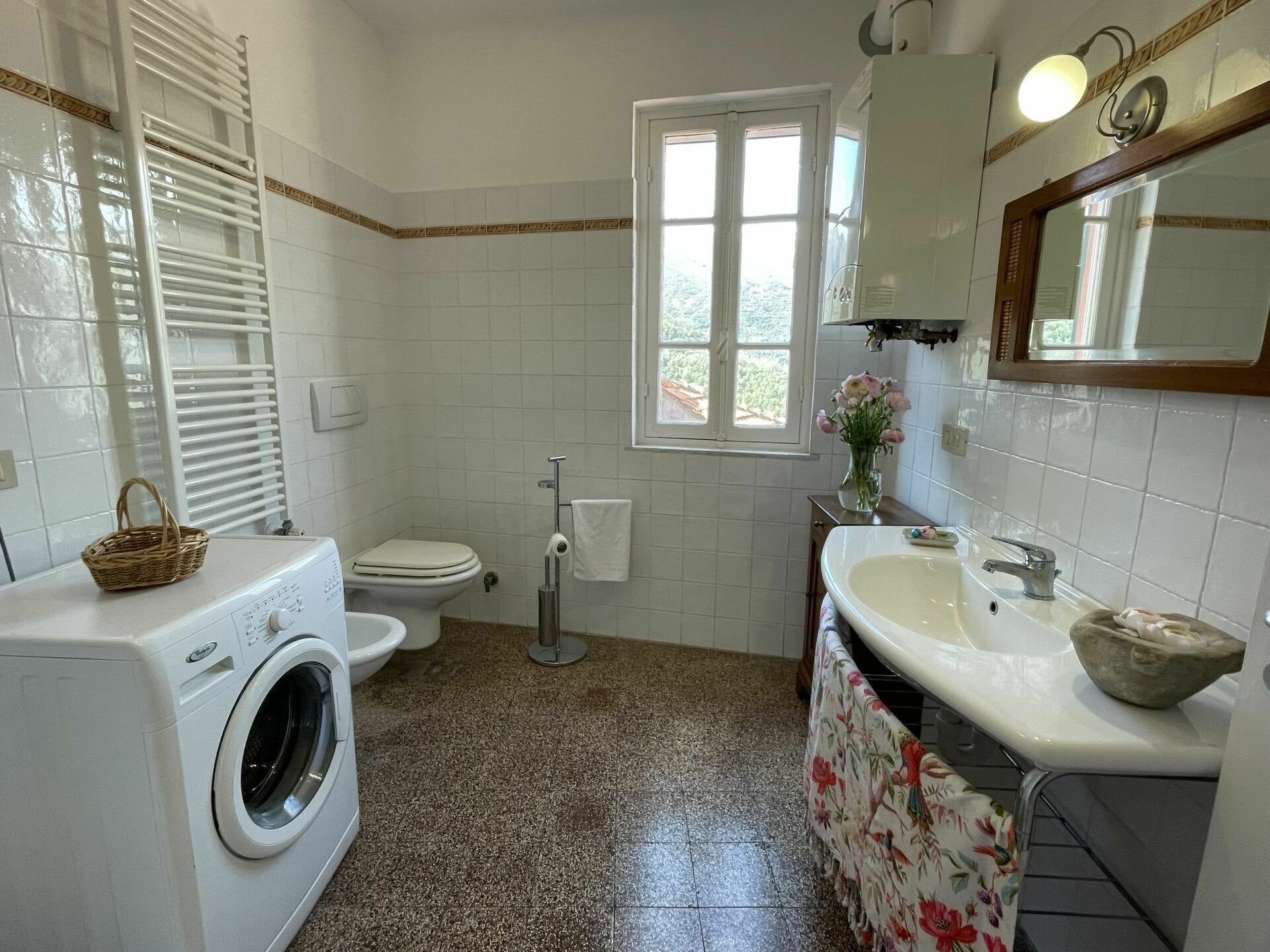 A bathroom with a washing machine, toilet, sink, and a window.