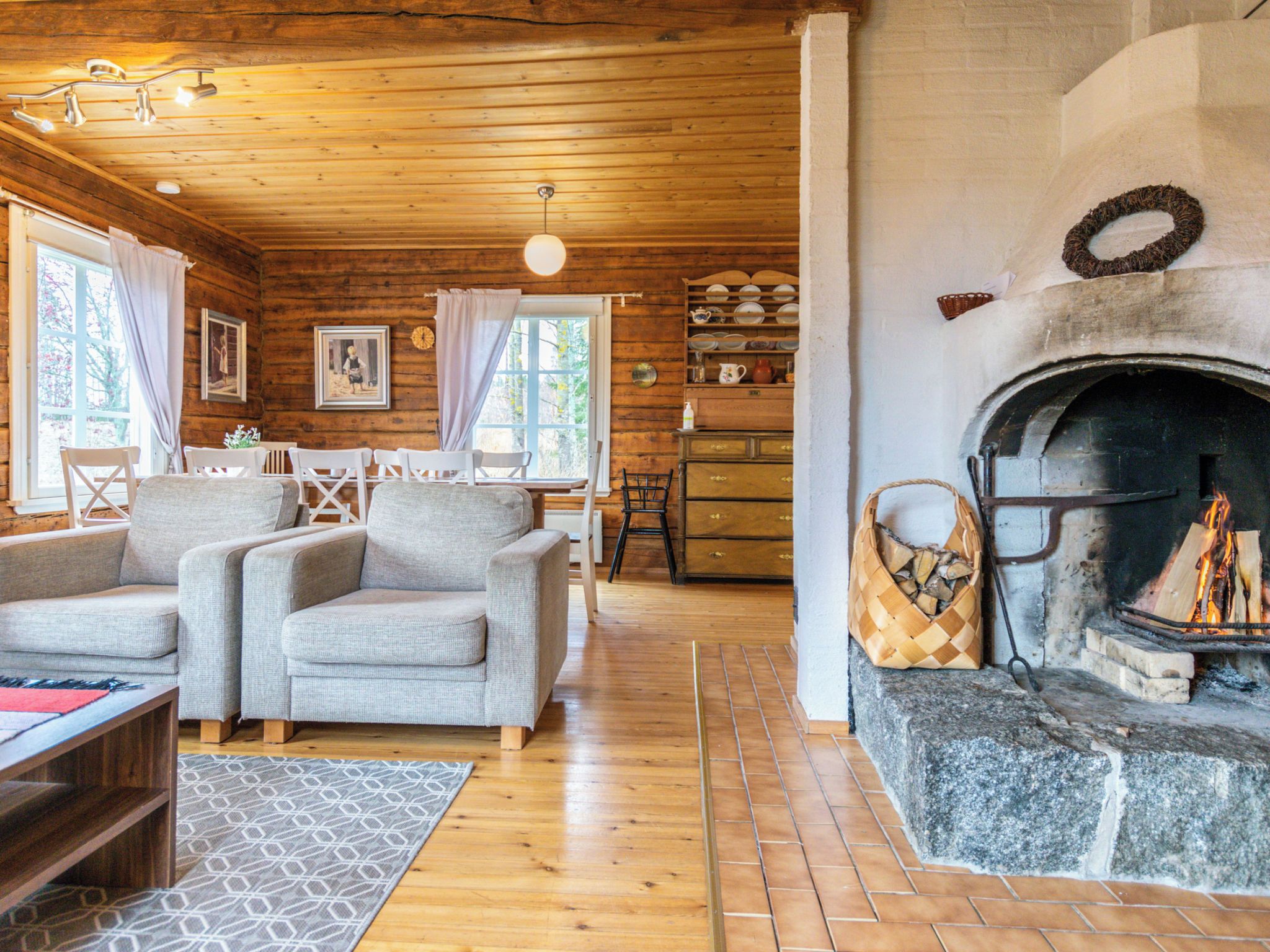 A cozy cabin interior with a fireplace, wooden walls, and a dining area.
