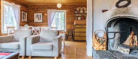 A cozy cabin interior with a fireplace, wooden walls, and a dining area.