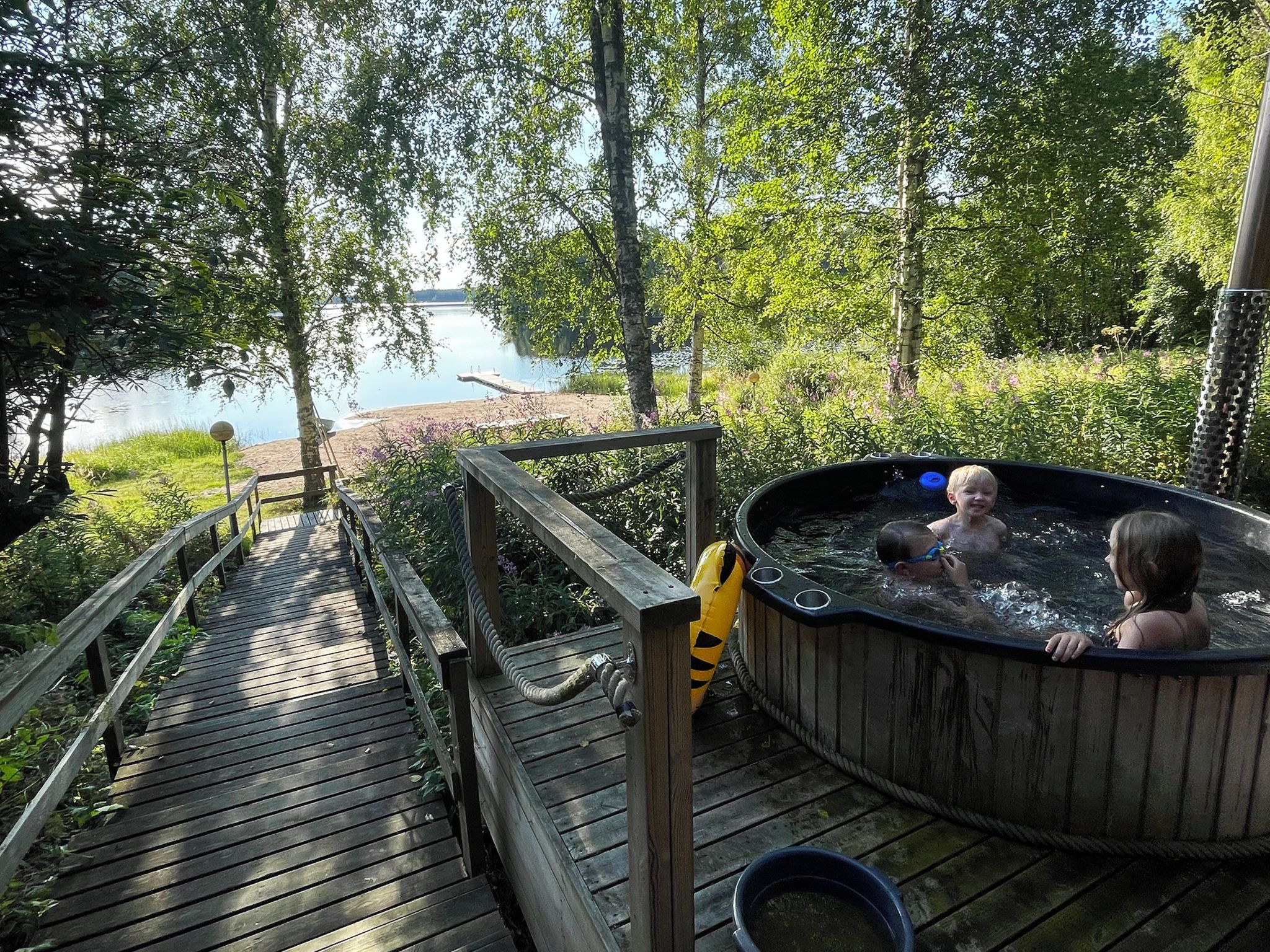 A wooden deck leading to a hot tub with a view of a lake.