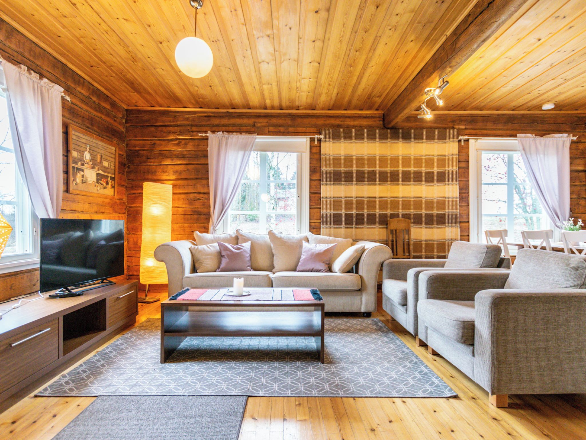 Een gezellig cabin interieur met een houten plafond, een zithoek, een televisie en een open haard.