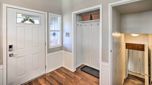 A hallway with white doors, a window with a wreath, a coat rack, and a wooden floor. - Sioux Center Split-Level Home w/ Game Room! (Sioux Center)