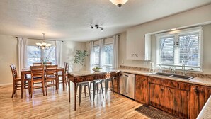 A kitchen with wooden flooring, a dining table with chairs, a built-in dishwasher, and a window with blinds. - Sioux Center Split-Level Home w/ Game Room! (Sioux Center)