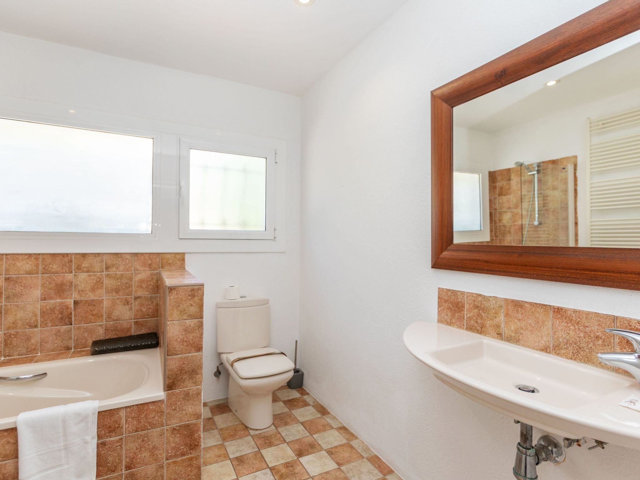 A bathroom with a bathtub, toilet, sink, and a mirror.