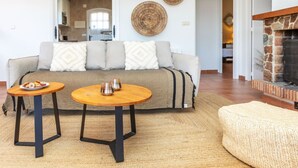 A living room with a sofa, two coffee tables, a fireplace, and a kitchen in the background. - El Suro by Interhome (Calonge)