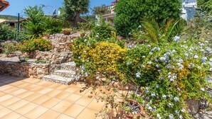 A garden with stone steps, various plants, and a tiled patio area. - El Suro by Interhome (Calonge)