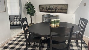 A dining area with a round table, black chairs, a potted plant, and a wall-mounted painting. - THUNDERDOME (awesome Dome House) Unique home with Beautiful views/Comfy and Cozy (Erie)