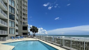 A swimming pool with a view of the ocean and a tall building in the background. - Oceanfront Condo in Garden City Beach!!!! (murrells inlet)