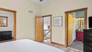 Un dormitorio con cama, cómoda, espejo y puerta que da a otra habitación.