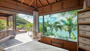 Une chambre avec une grande fenêtre, un plafond en bois et une vue sur des palmiers et une plage.