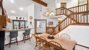 Eine geräumige Küche mit einer Holztischinsel, einem Essbereich mit Holztisch und Stühlen sowie einer Treppe, die zu einer oberen Ebene führt.