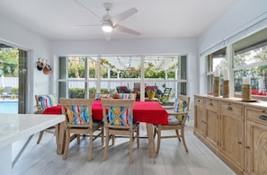 Una cocina luminosa con comedor, ventanas amplias y ventilador de techo.