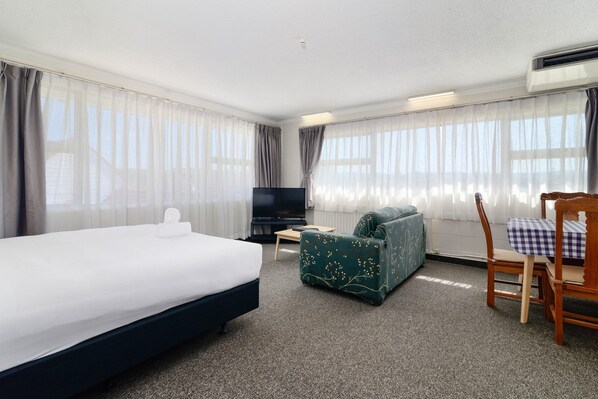 Une chambre d’hôtel avec un lit, un canapé, une télévision et une chaise.