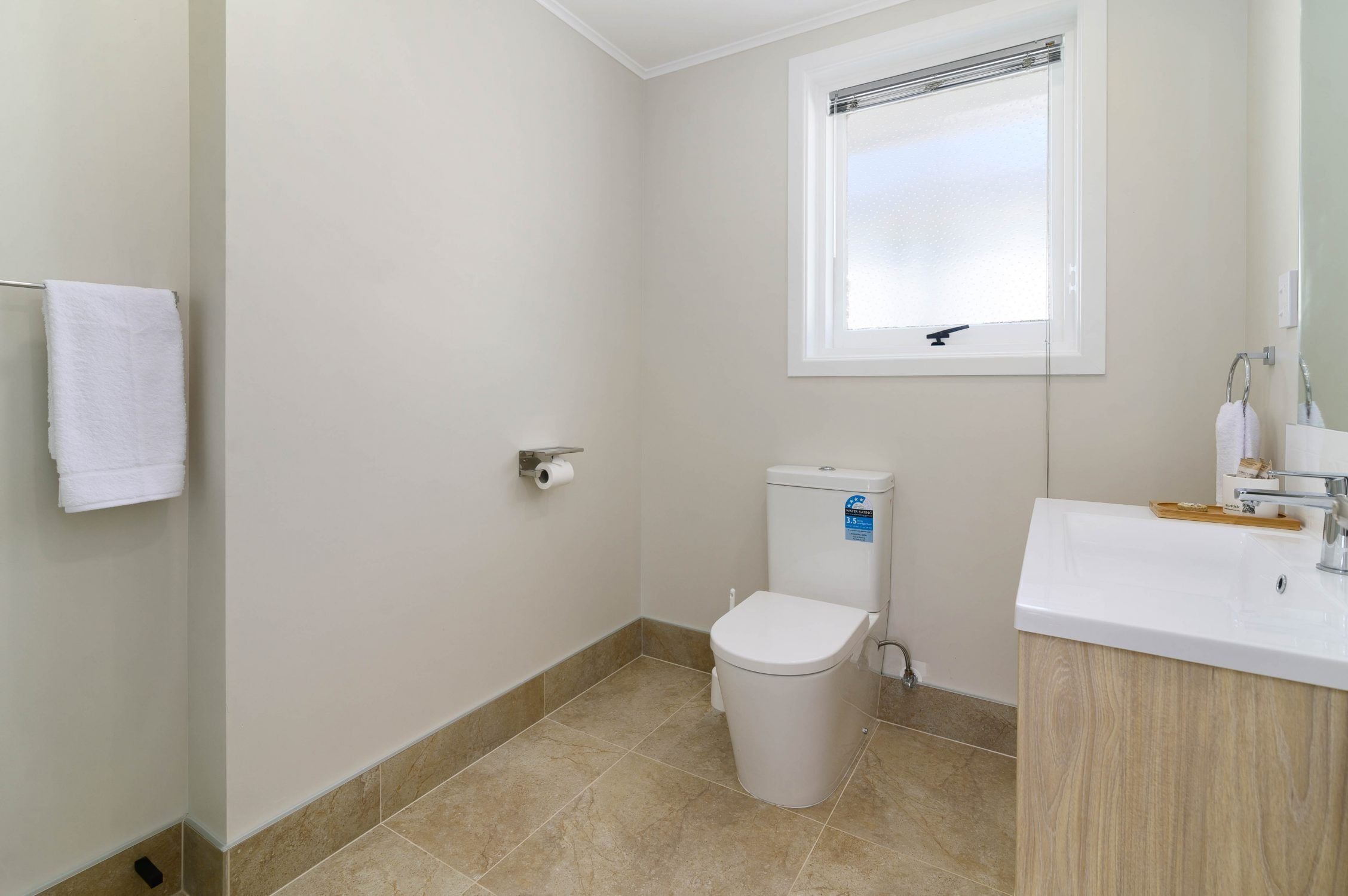 A bathroom with a toilet, sink, and a window.