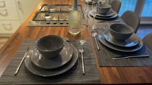 Une table à manger dressée avec des bols, des assiettes et des couverts noirs, une bouteille de champagne et des verres à vin.