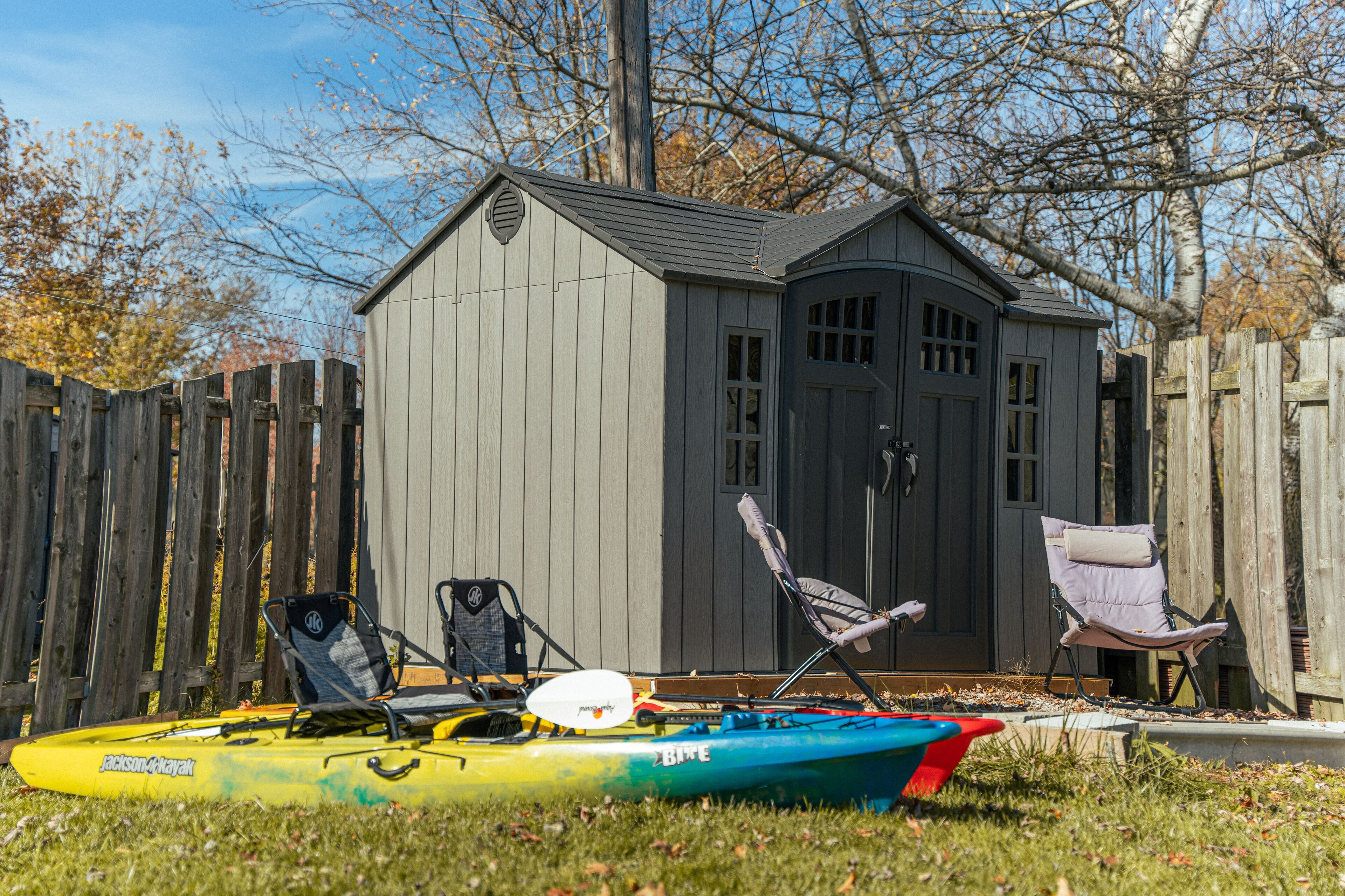 A kayak and chairs in front of a shed.