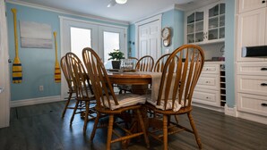 A dining area with a wooden table and chairs, a ceiling fan, and a view of the kitchen in the background. - Private Lakefront House with Hot Tub, Kayaks and Beach (Selkirk)