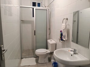 Kylpyhuone, jossa on wc, pesuallas ja lasinen suihkuseinä.