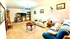 Una sala de estar con sofá, sillón, mesa de centro y estantería.