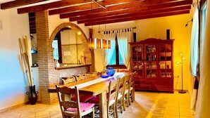 Comedor con una larga mesa de madera, sillas y una chimenea de ladrillo.