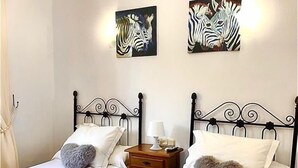 Un dormitorio con dos camas individuales, una mesita de noche y dos cuadros de cebra colgados en la pared.