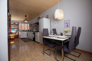 Une cuisine moderne avec un coin repas, comprenant une table à manger pour quatre personnes, un réfrigérateur et un luminaire suspendu.