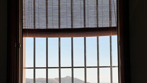 Ein Fenster mit Blick auf einen Weinberg und Hügel.