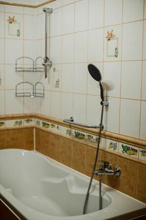 A bathroom with a bathtub, a handheld showerhead, and a towel rack. - Star Hamry Mosl590 (Staré Hamry)