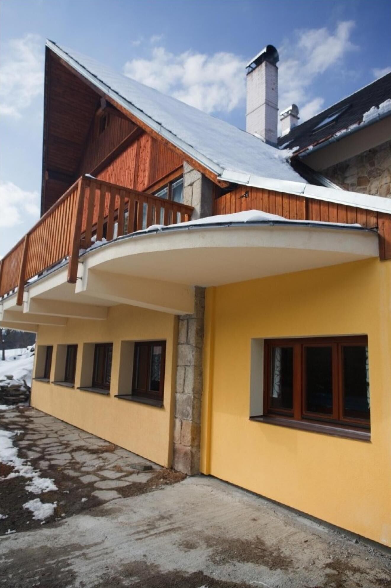 A yellow building with a wooden balcony and a stone pillar.